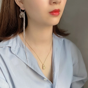 Detail of elegant silver tassel earrings and gold bear necklace worn by a model