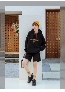 Close-up of black hoodie set with orange text print and yellow knit hat styling