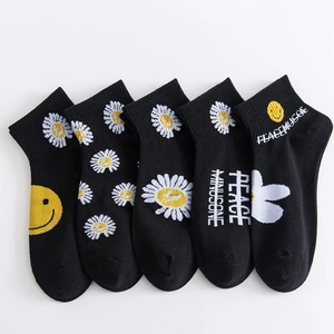 Close-up of five pairs of black cotton socks with white daisy and peace minusone patterns