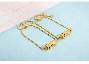 Detail of adjustable gold box chain bracelets with heart charms and letter cubes
