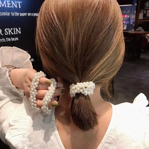 Detail of multi-layer white pearl hair tie showing glossy beads and elastic texture