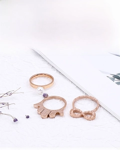 Detailed view of rose gold ring set featuring pearl, Hand of Fatima, and infinity designs