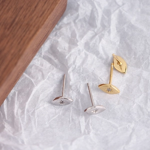 Close-up of gold and silver minimalist eye-shaped stud earrings with sparkling crystals