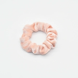 Detailed texture of pink velvet scrunchie showing glossy fabric and elastic design