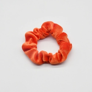 Detail of vibrant orange velvet scrunchie showing soft texture and high elasticity
