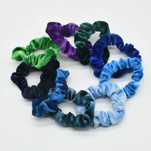 Close-up of assorted colorful velvet scrunchies in vibrant blue, green, and purple tones