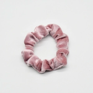 Close-up of pink velvet scrunchie showing soft pleated texture and fabric details