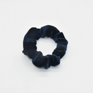 Detailed close-up of dark blue velvet fabric texture on a soft elastic hair scrunchie