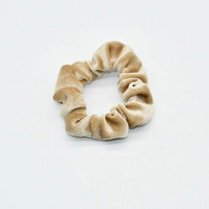 Close-up of light brown velvet scrunchie showing detailed fabric texture and pleats