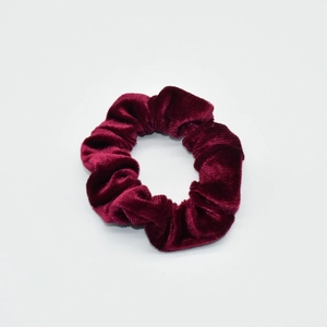 Macro detail of wine red velvet fabric texture on elastic scrunchie hair accessory