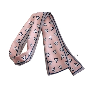 Pink narrow silk scarf with black heart pattern and dark blue borders on white surface