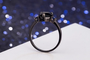 Macro detail of black heart gemstone ring with side stones on a dark bokeh background