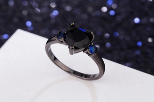Macro shot of S925 engraved black ring featuring a heart gem and blue side stones