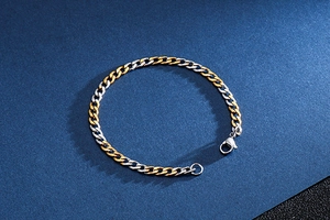 Detail shot of a two-tone gold and silver Cuban chain bracelet with a secure lobster clasp