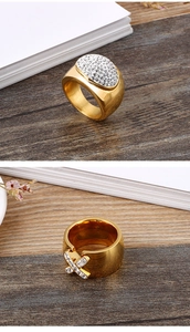 Macro detail of gold anchor ring with pavé crystals and cross motif on wide band
