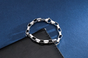 Macro detail of silver rectangular link chain bracelet with secure lobster clasp