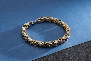 Detailed close-up of two-tone gold and silver Byzantine chain bracelet on a desk