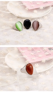 Macro view of teardrop cat eye stone rings in emerald and purple with silver bands