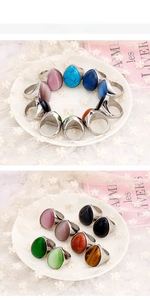 Detailed view of teardrop gemstone rings in various colors on a lace background