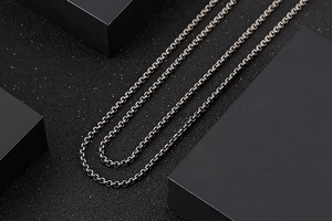 Close-up of a classic stainless steel O-chain necklace draped over black geometric blocks