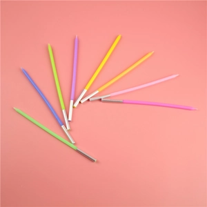 Detailed view of colorful slim birthday candles with silver holders on pink background