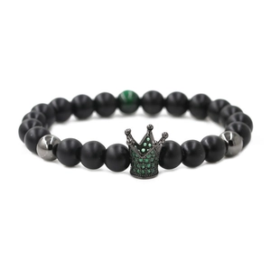 Detail of matte black beads bracelet with green zircon crown pendant close-up