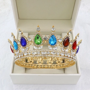 Detailed shot of a golden baroque crown with colorful gemstones in a white jewelry box