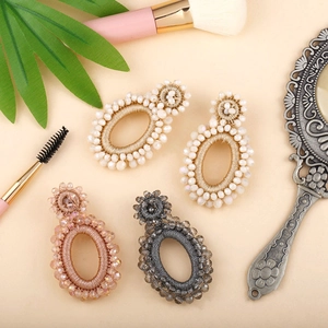 Flat lay of handmade bohemian beaded earrings in ivory, gold, and grey on a vanity