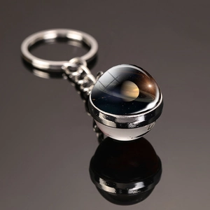 Macro shot of silver-toned metal Saturn keychain with double-sided glass galaxy pendant