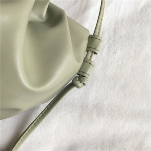 Detailed view of sage green pleated cloud bag featuring knotted shoulder strap texture