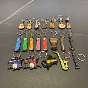 Detailed flat lay of various soft PVC musical instrument keychains on dark surface