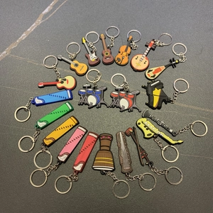 Assorted musical instrument PVC keychains including guitar and violin in a circular layout