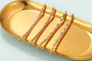 Close-up of vibrant enamel evil eye charms on adjustable gold-plated bracelets