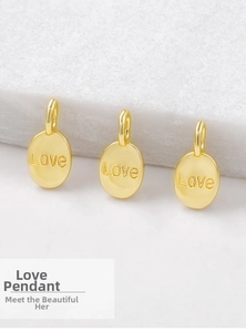 Detailed view of three gold oval love pendants with smooth finish on marble surface