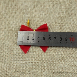 Close-up measurement of a 4.5cm red velvet Christmas bow with gold twist ties