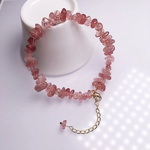 Pink strawberry quartz beaded bracelet with adjustable gold lobster clasp on white stand