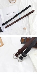 Detail of slim leather belts with D-ring metal buckles in black and brown colors