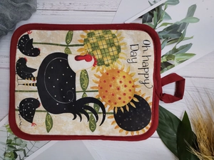 Close-up of a thick cotton kitchen mat featuring sunflower and chicken motifs with red piping