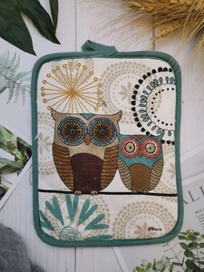 Flat lay of cotton owl printed thick oven mat with hanging loop on white wood background