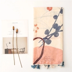 Floral print scarf in beige with blue tassels, styled with a minimalist magazine