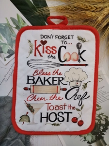 Close-up of cotton baking mat with red trim and printed kitchen quotes on wood surface
