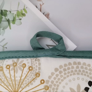 Close-up of thick cotton oven mat with floral print, green piping and hanging loop