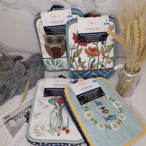 Kitchen textile set with floral oven mitts and pot holders on a marble background