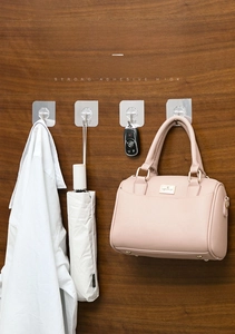 Strong transparent adhesive wall hooks holding heavy bags and keys on a wooden surface
