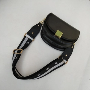 Detail of black semi-circle saddle bag with star pattern wide woven strap and gold buckle
