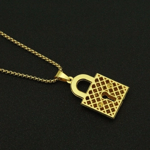 Macro shot of gold box chain and iced-out padlock pendant with keyhole on black surface