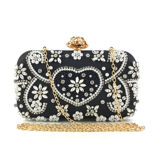 Detail of black evening clutch with heart pearl embroidery and gold floral clasp