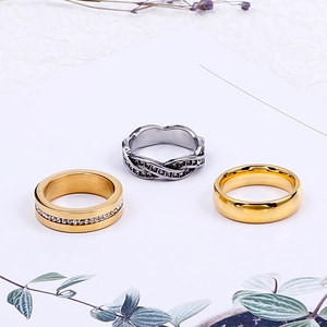 Three minimalist stainless steel rings in gold and silver finishes with micro-inlay accents