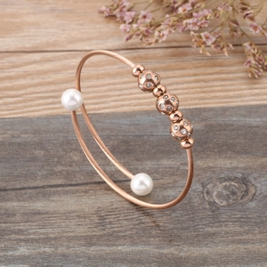 Détail d'un bracelet en fil d'or rose avec perles et billes serties de zircons sur bois