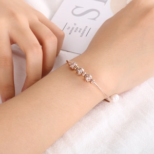 Vue détaillée du bracelet en fil d'or rose avec sphères en zircone et une perle blanche